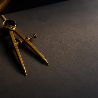 A brass drafting compass resting on a blank plan.
